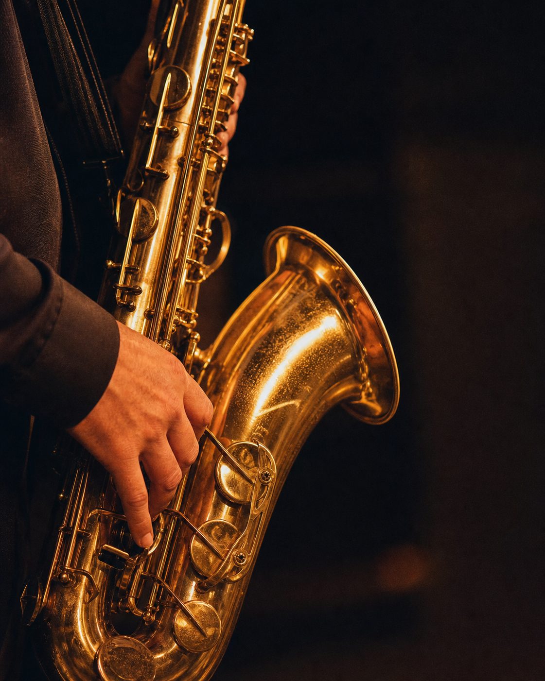 Nahaufnahme eines Saxofons im goldenen Bühnenlicht vor dunklem Hintergrund.